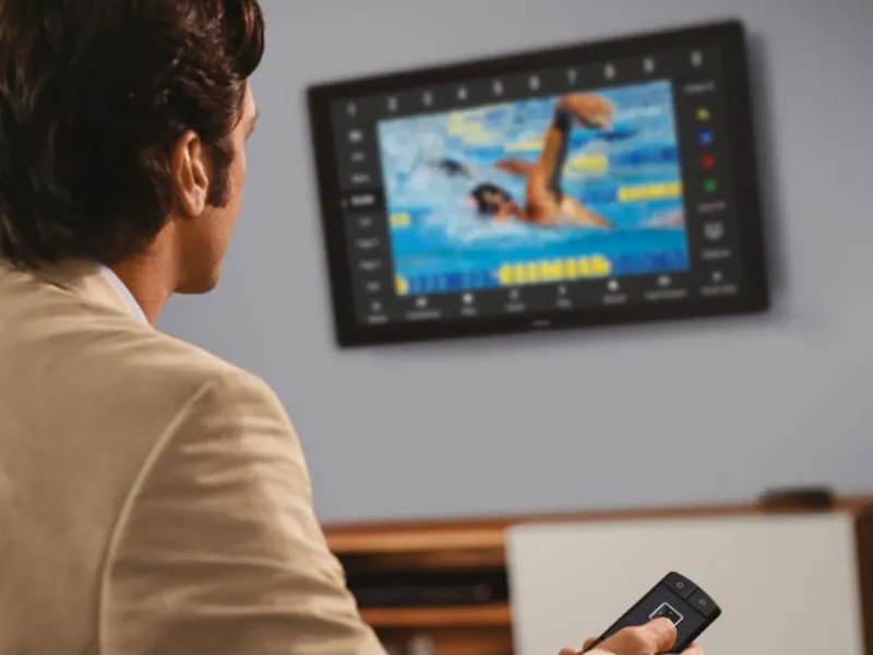 uomo con telecomando e schermo tv a parete con nuotatore