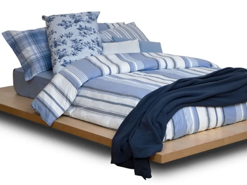 letto matrimoniale con copripiumino a righe sui toni dl blu e cuscini abbianti, coperta blu scuro