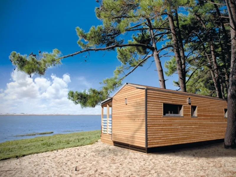 mobile cucina bianco panna con pannello muro marrone scuro, soffitto spiovente, pareti e pavimento on legno chiaro, divano antracite