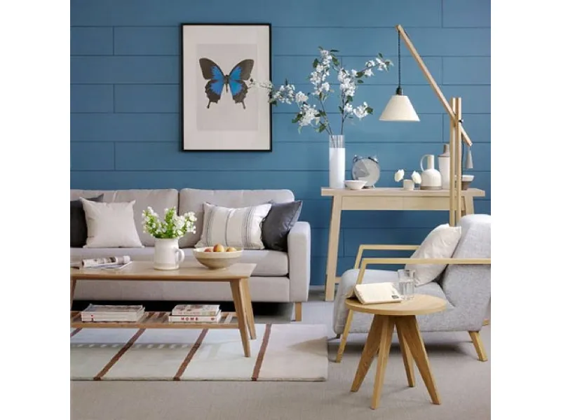 Divano e arredi di colore beige accostati ad un muri dipinto di azzurro intenso