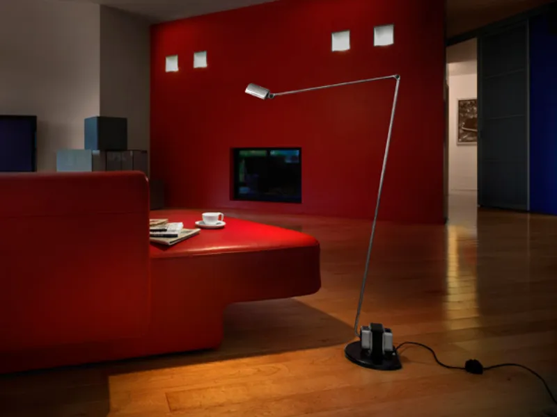 zona living con parete e divano con tavolino incorporato rosso, lampada da terra con braccio in acciaio articolato