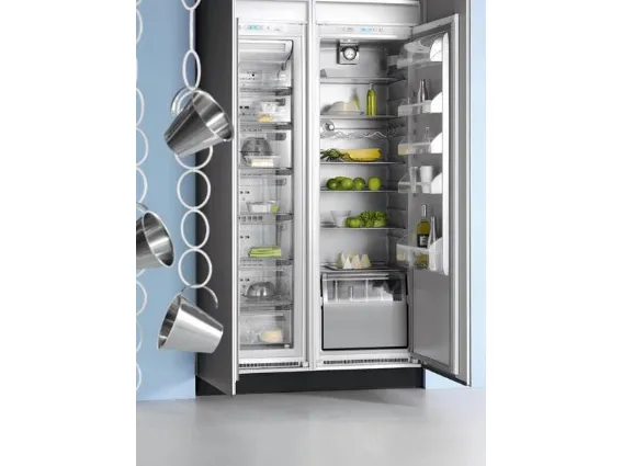 frigo a doppia porta aperto con ananas, lime, bottiglie e contenitori, tre pentolini sospesi su una catena