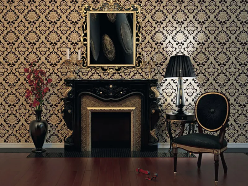 dettaglio zona living nei colori nero e oro co parquet in legno, caminetto, poltrona, abat-jour, vaso con fiori rossi e cornice