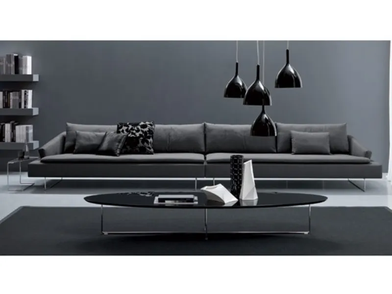 divano lungo con struttura in acciaio e cuscinature color antracite, lampadari a soffitto neri e tavolino ovale nero