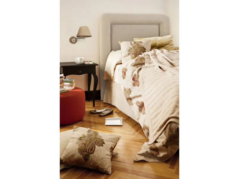 letto matrimoniale con tessili e cuscini color panna con fantasie floreali jacquard, pouf rosso