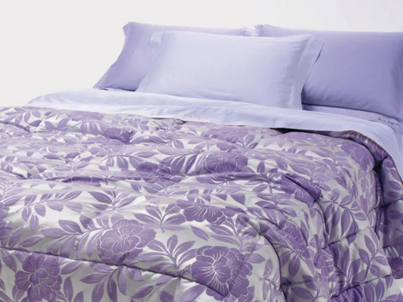 letto matrimoniale con biancheria lavanda e copriletto a fantasia floreale viola e argento