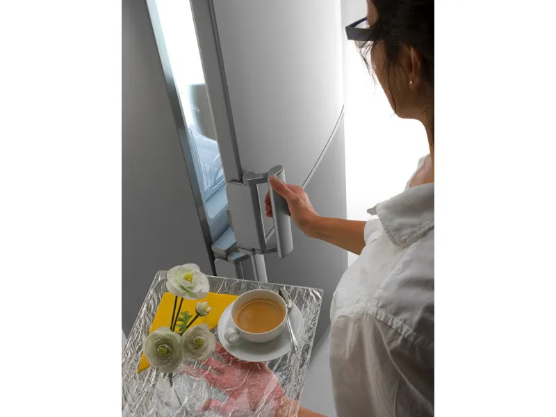 donna con vassoio con tè e fiori apre l'anta superiore del frigo 
