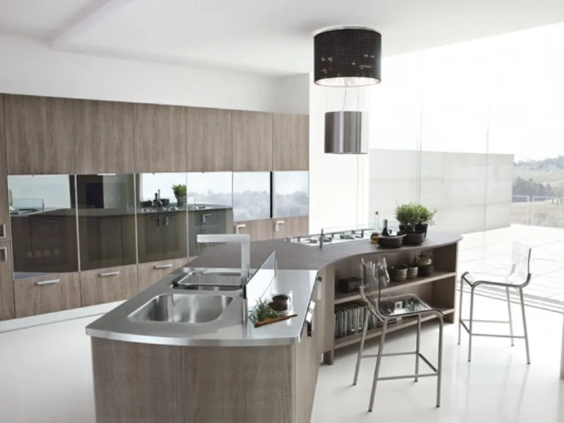 cucina in legno e acciaio con dettagli a specchio su armadiatura, isola centrale con lavabo, piano cottura, piano di lavoro e tavolo snack con due sgabelli