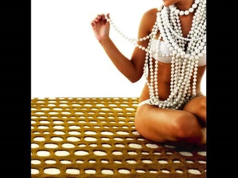 donna in bikini con collana a multipil giri di perle su tappeto con fori circolari