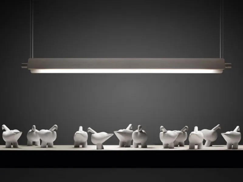Lampadario in legno che illumina ripiano con complementi d'arredo a forma di colombe.